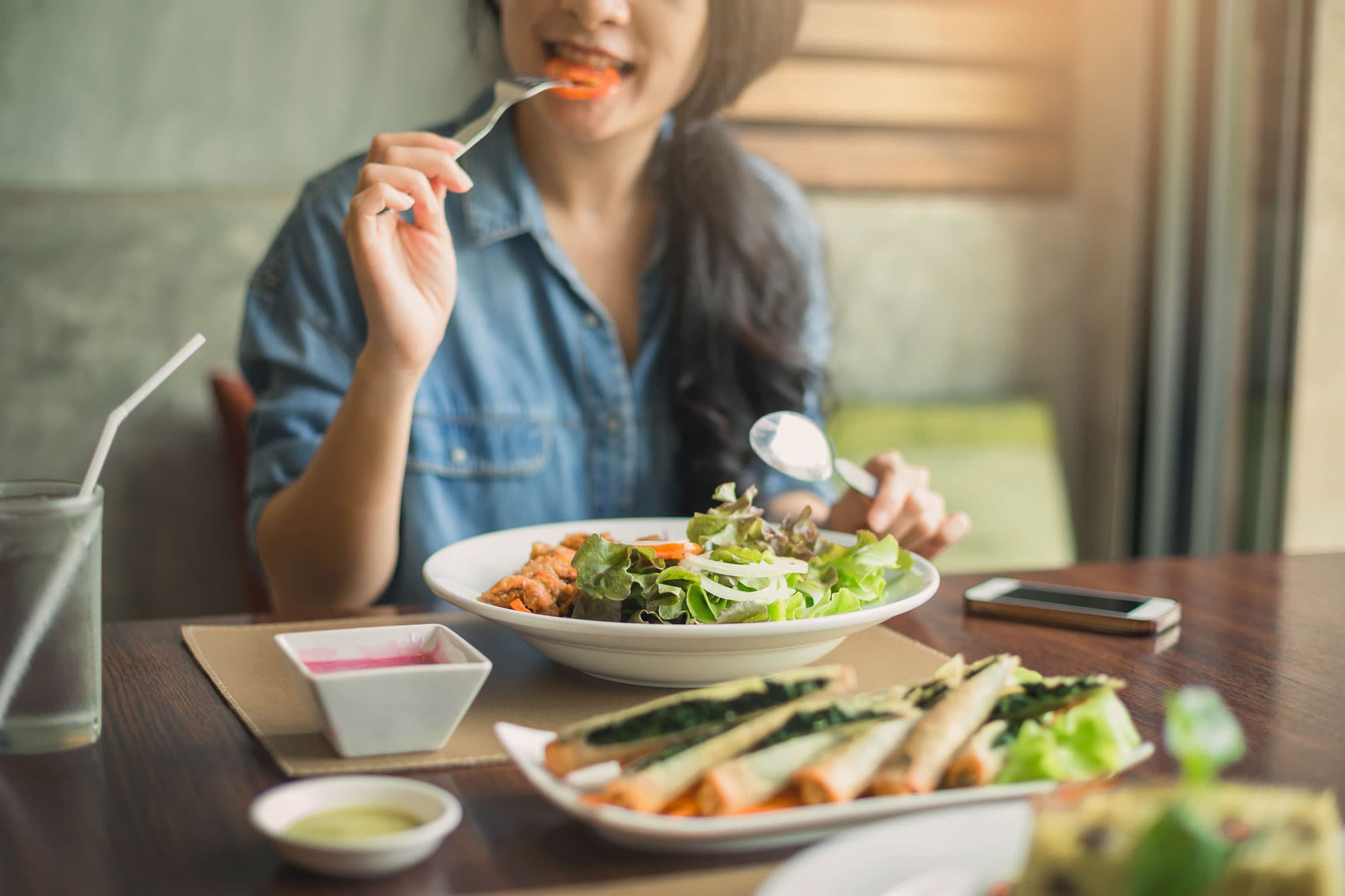 A woman eating salad with a fork.